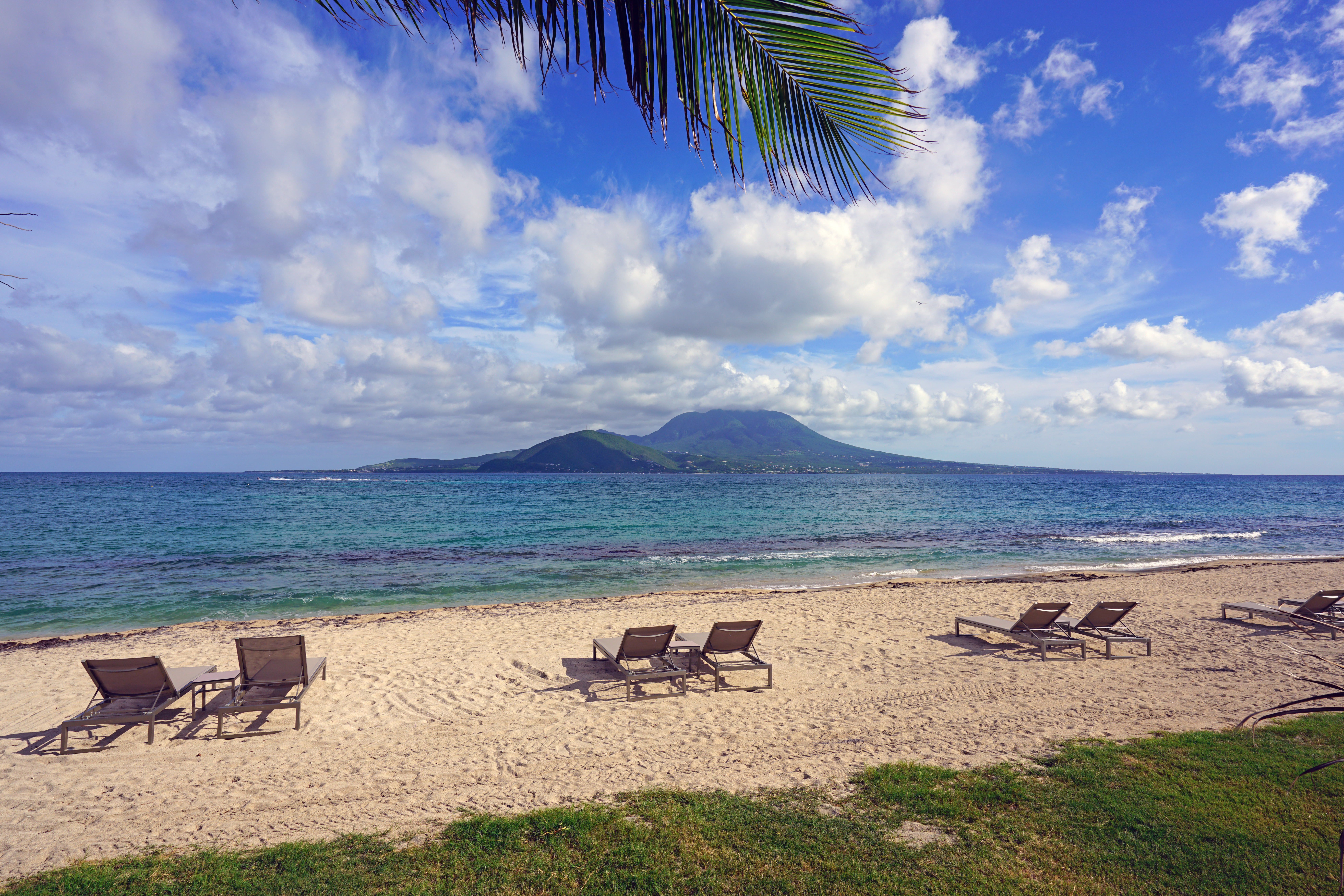 Beach chairs overlooking turquoise water with Nevis in the background