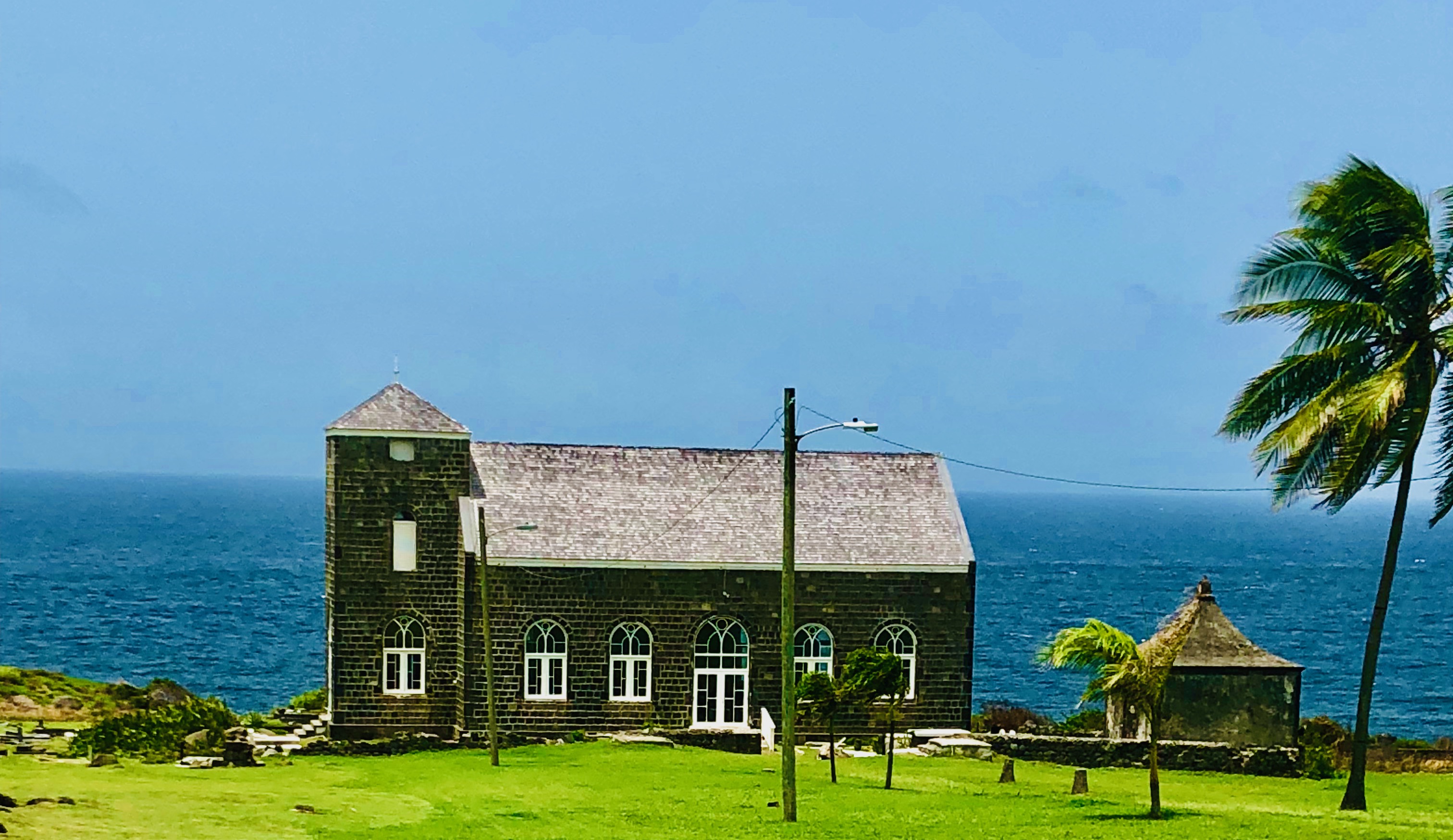Historic stone church on the coast with palm tree