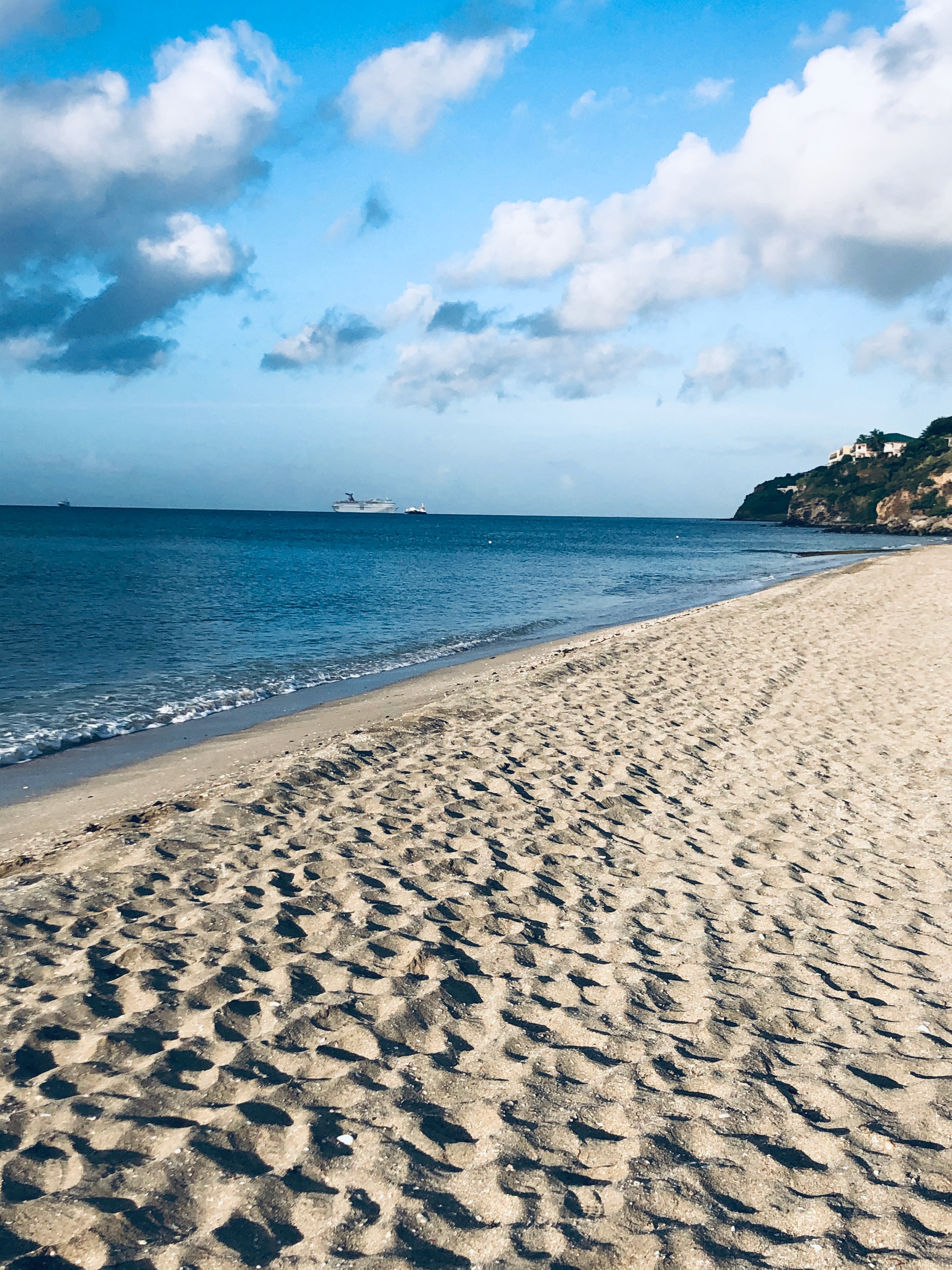 Pristine sandy beach with cruise ship in the distance